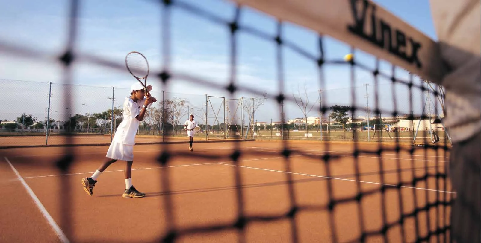 A student playing tennis on the TVIS courts